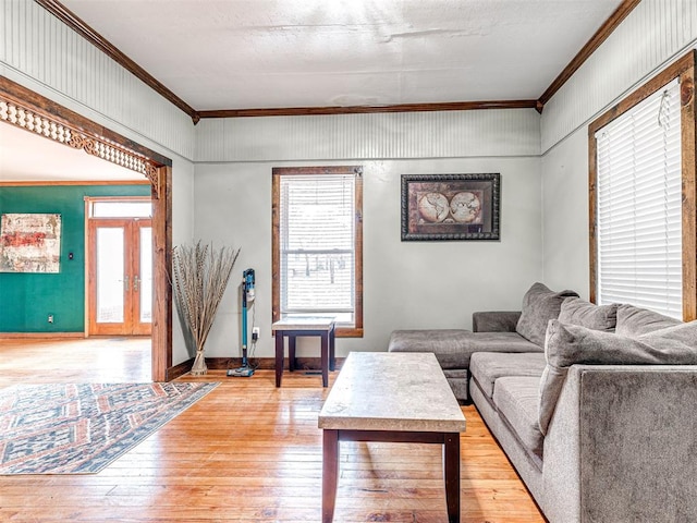 living room featuring hardwood / wood-style flooring, ornamental molding, french doors, and a wealth of natural light