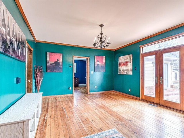 interior space with hardwood / wood-style flooring, crown molding, a notable chandelier, and french doors