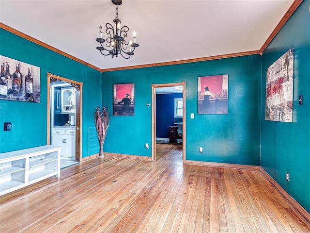 spare room with hardwood / wood-style flooring, ornamental molding, and a notable chandelier