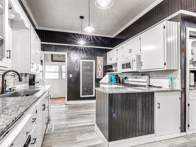 kitchen with light stone counters, sink, stove, and white cabinets