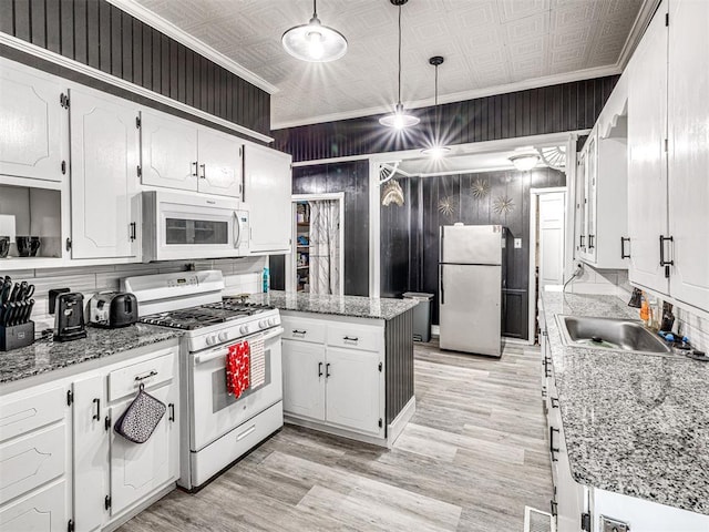 kitchen featuring sink, white cabinetry, crown molding, hanging light fixtures, and white appliances