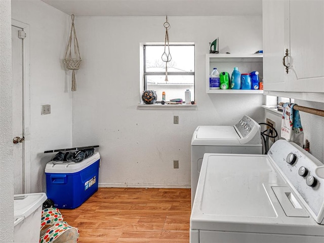 clothes washing area with cabinets, light hardwood / wood-style floors, and washer and dryer