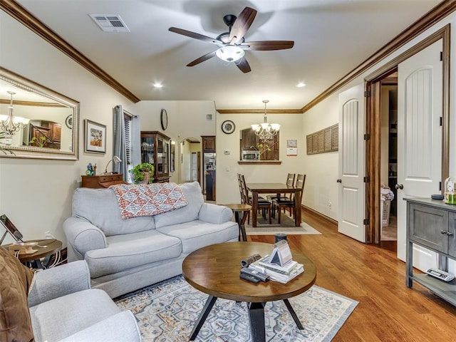 living room featuring ceiling fan with notable chandelier, ornamental molding, and light hardwood / wood-style floors