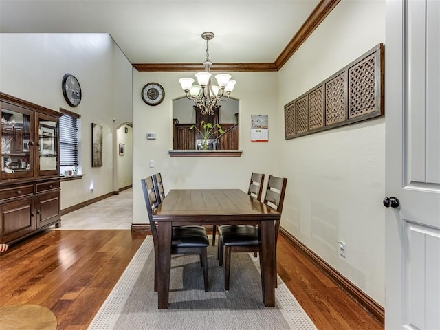 dining room with ornamental molding, a notable chandelier, and light wood-type flooring