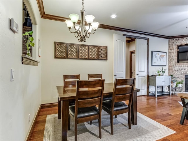 dining space with dark hardwood / wood-style flooring, crown molding, a fireplace, and an inviting chandelier