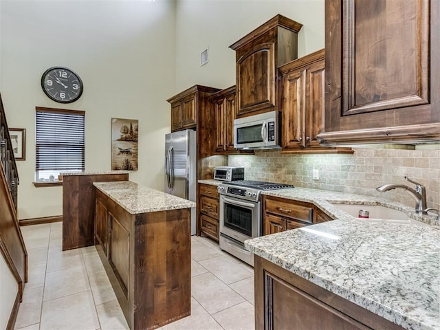 kitchen with light stone counters, sink, light tile patterned floors, and appliances with stainless steel finishes