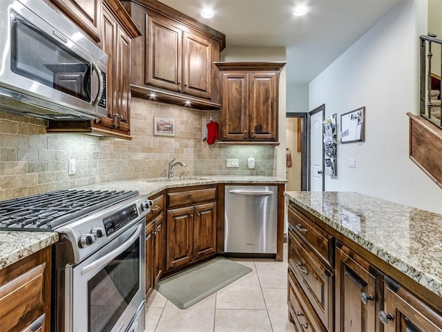 kitchen featuring light stone counters, appliances with stainless steel finishes, sink, and light tile patterned floors