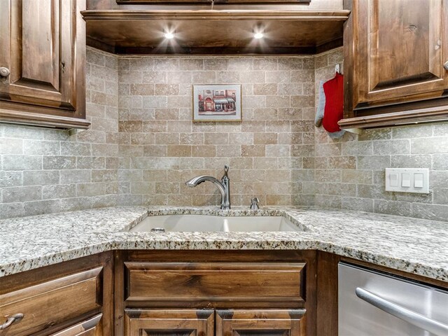 kitchen featuring dishwasher, light stone countertops, sink, and backsplash
