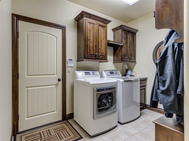 laundry room featuring independent washer and dryer, cabinets, and light tile patterned flooring