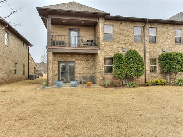 back of property featuring french doors, a balcony, a yard, and central air condition unit