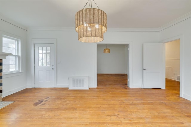 interior space featuring ornamental molding, a notable chandelier, and light hardwood / wood-style floors