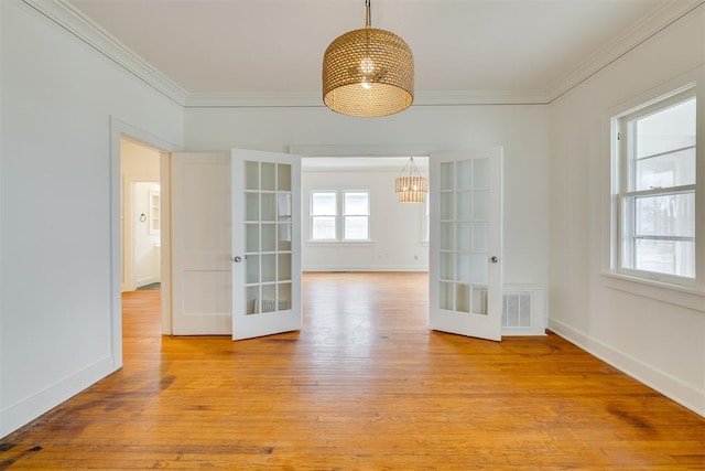 empty room with light hardwood / wood-style flooring, ornamental molding, and french doors