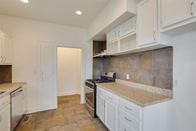 kitchen with white cabinetry, stainless steel appliances, light stone countertops, and backsplash