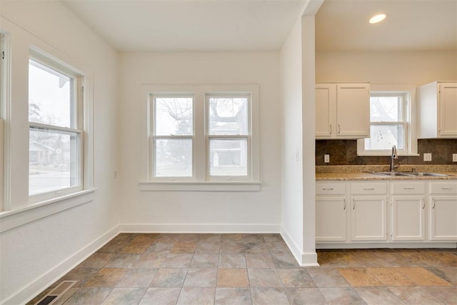 kitchen featuring white cabinetry, light stone countertops, sink, and decorative backsplash