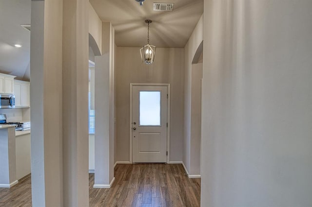 entryway featuring baseboards, visible vents, arched walkways, and wood finished floors