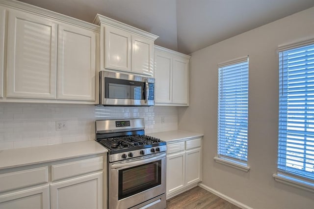 kitchen with stainless steel appliances, a wealth of natural light, white cabinets, and decorative backsplash