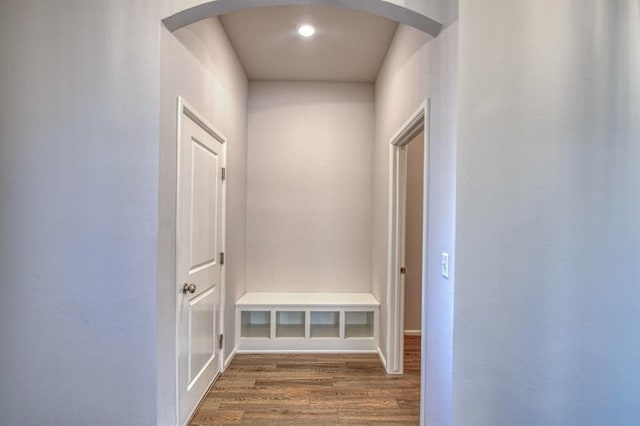 hallway featuring arched walkways and wood finished floors