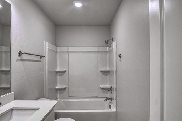 bathroom with tub / shower combination, a textured wall, vanity, and toilet