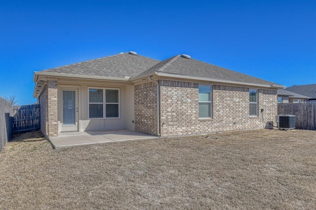 back of property with a fenced backyard, roof with shingles, a yard, a patio area, and brick siding