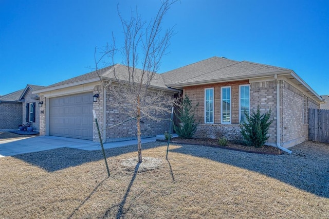 view of front facade with a garage, brick siding, driveway, and fence