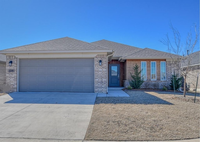 single story home featuring a garage, a shingled roof, concrete driveway, and brick siding