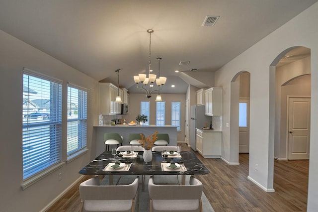 dining area with baseboards, visible vents, arched walkways, dark wood finished floors, and a chandelier