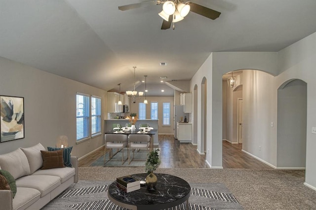 living room featuring arched walkways, a healthy amount of sunlight, vaulted ceiling, and baseboards