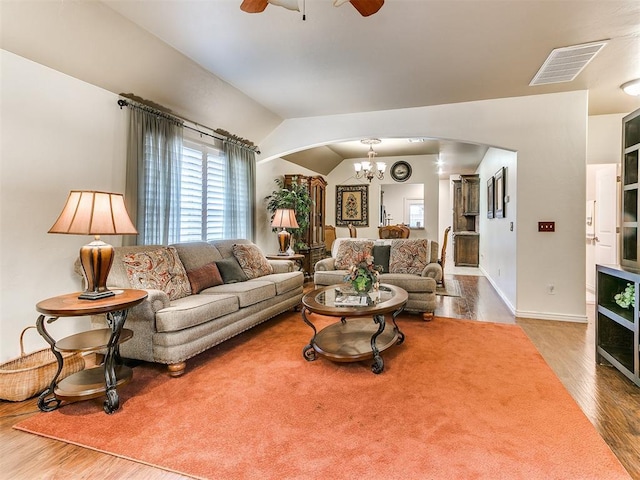 living room featuring lofted ceiling, ceiling fan with notable chandelier, and wood-type flooring