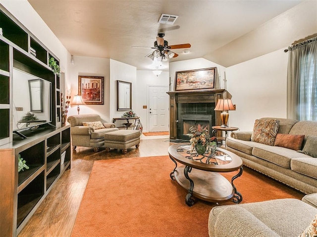 living room with a tile fireplace, lofted ceiling, hardwood / wood-style floors, and ceiling fan