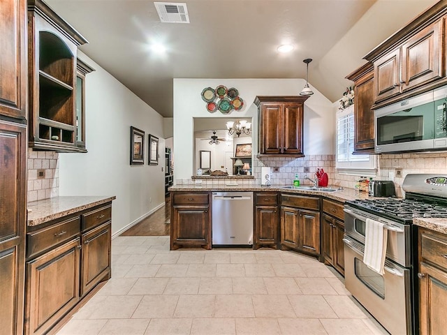 kitchen with lofted ceiling, sink, light stone counters, stainless steel appliances, and decorative backsplash