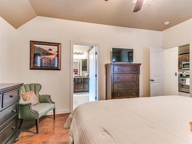 bedroom with vaulted ceiling, connected bathroom, ceiling fan, and light hardwood / wood-style floors