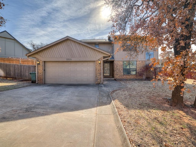 view of front facade featuring an attached garage, fence, concrete driveway, and brick siding