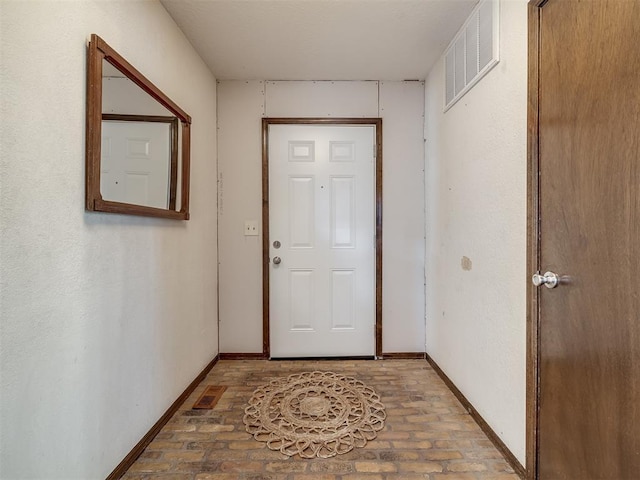 entryway featuring brick floor, visible vents, and baseboards