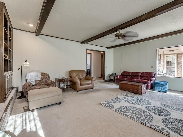 carpeted living area featuring a textured ceiling, ceiling fan, and beam ceiling