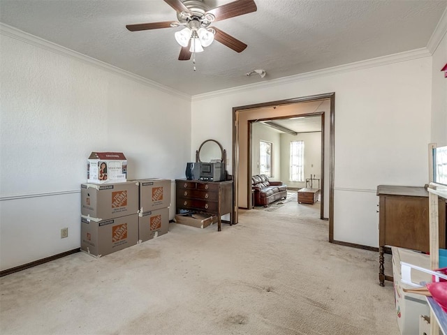 interior space featuring a textured ceiling, carpet flooring, a ceiling fan, baseboards, and ornamental molding