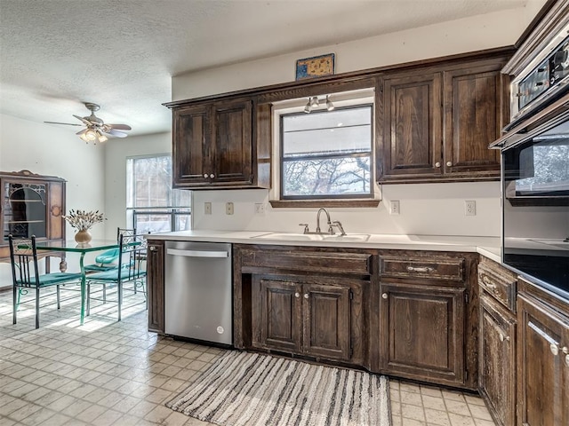 kitchen featuring light floors, stainless steel dishwasher, a sink, and dark brown cabinetry