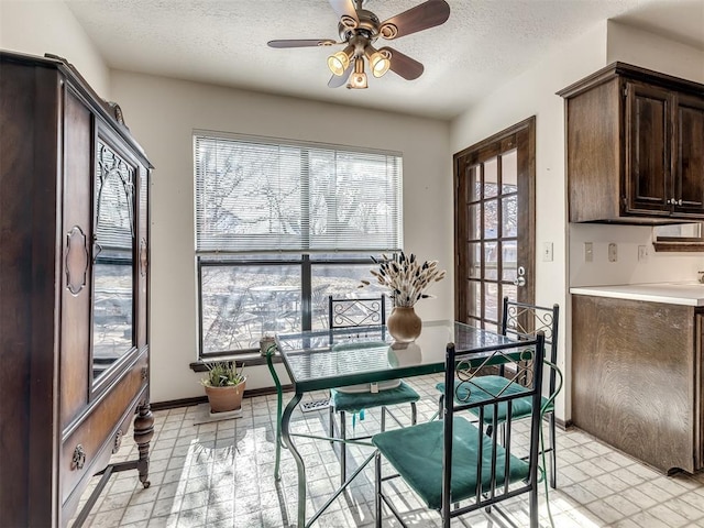 dining area with a textured ceiling, a ceiling fan, and baseboards