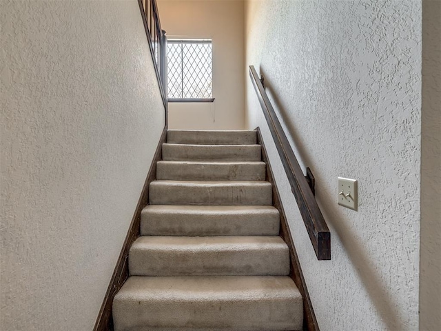 staircase featuring a textured wall