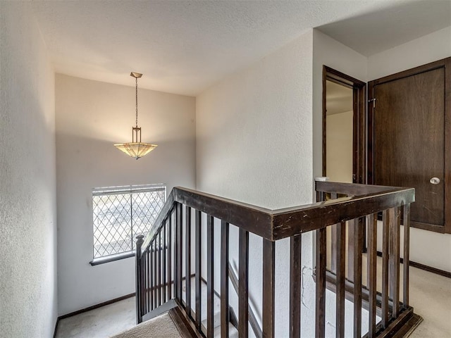 staircase with a textured ceiling, a textured wall, carpet flooring, and baseboards