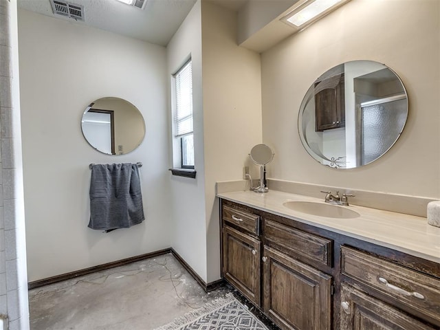 bathroom featuring visible vents, vanity, baseboards, and walk in shower