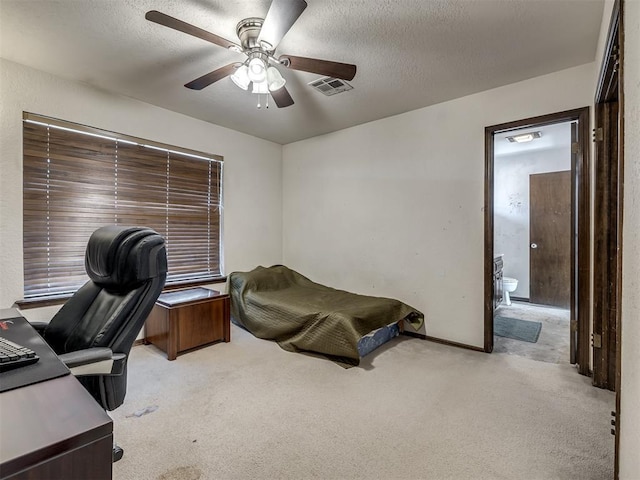 home office with a textured ceiling, a ceiling fan, visible vents, and light colored carpet