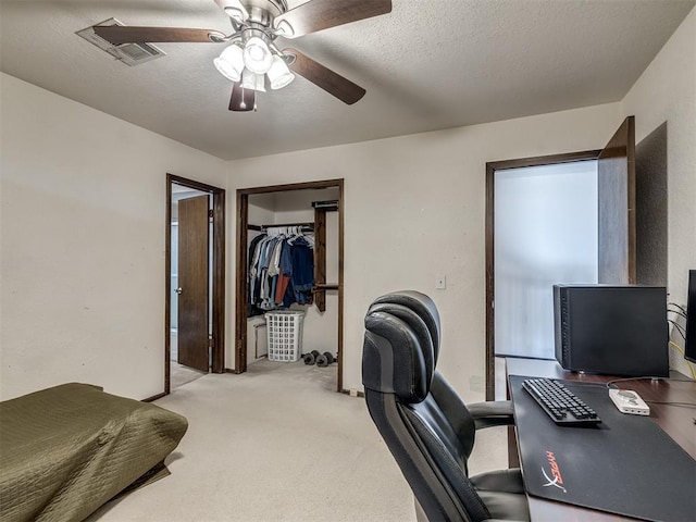 office space with a ceiling fan, visible vents, a textured ceiling, and light colored carpet