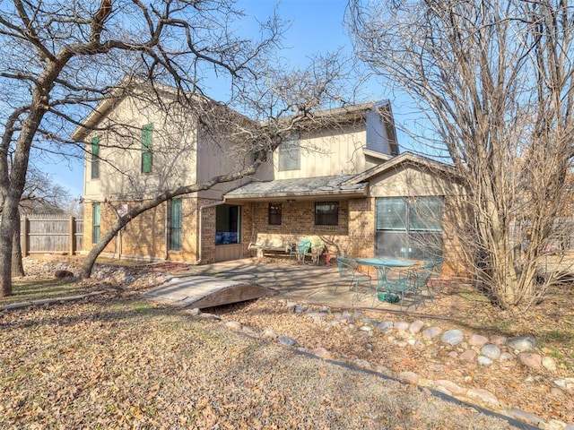 back of house with brick siding, roof with shingles, a patio area, and fence