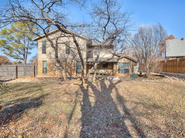 back of house with brick siding and fence