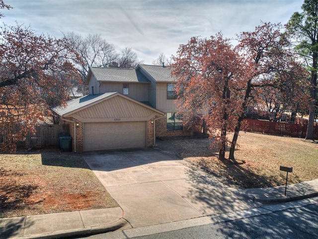 view of front facade featuring a garage, driveway, brick siding, and fence