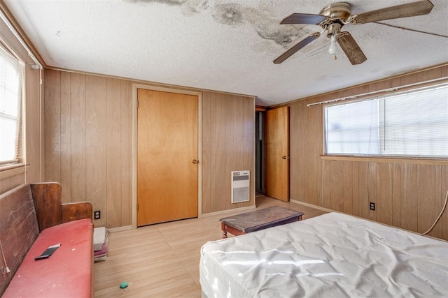 21731 E Fifth St, Hinton, OK 73047 - bedroom featuring heating unit, a textured ceiling, light wood-type flooring, and wood walls