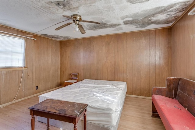 21731 E Fifth St, Hinton, OK 73047 - bedroom with wood walls, ceiling fan, and light wood-type flooring