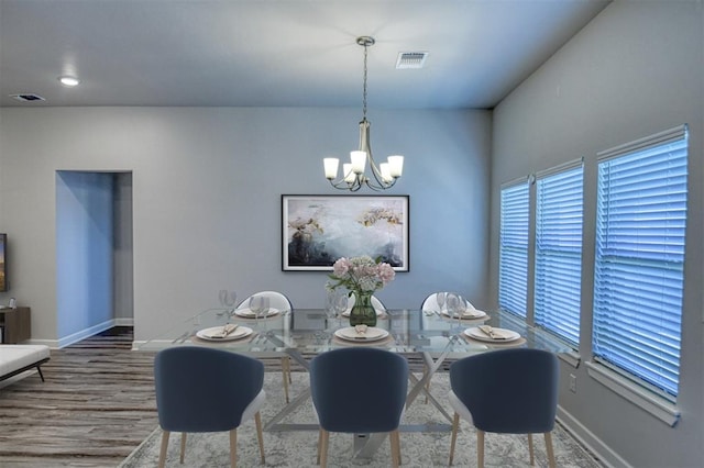 dining room with baseboards, visible vents, a notable chandelier, and wood finished floors