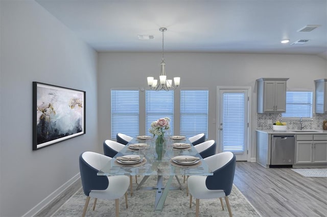 dining room with a chandelier, baseboards, visible vents, and light wood finished floors