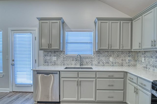 kitchen featuring a sink, vaulted ceiling, light countertops, gray cabinets, and dishwasher